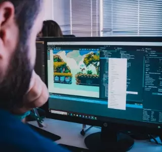 Un étudiant devant son ordinateur en train de créer un jeu vidéo